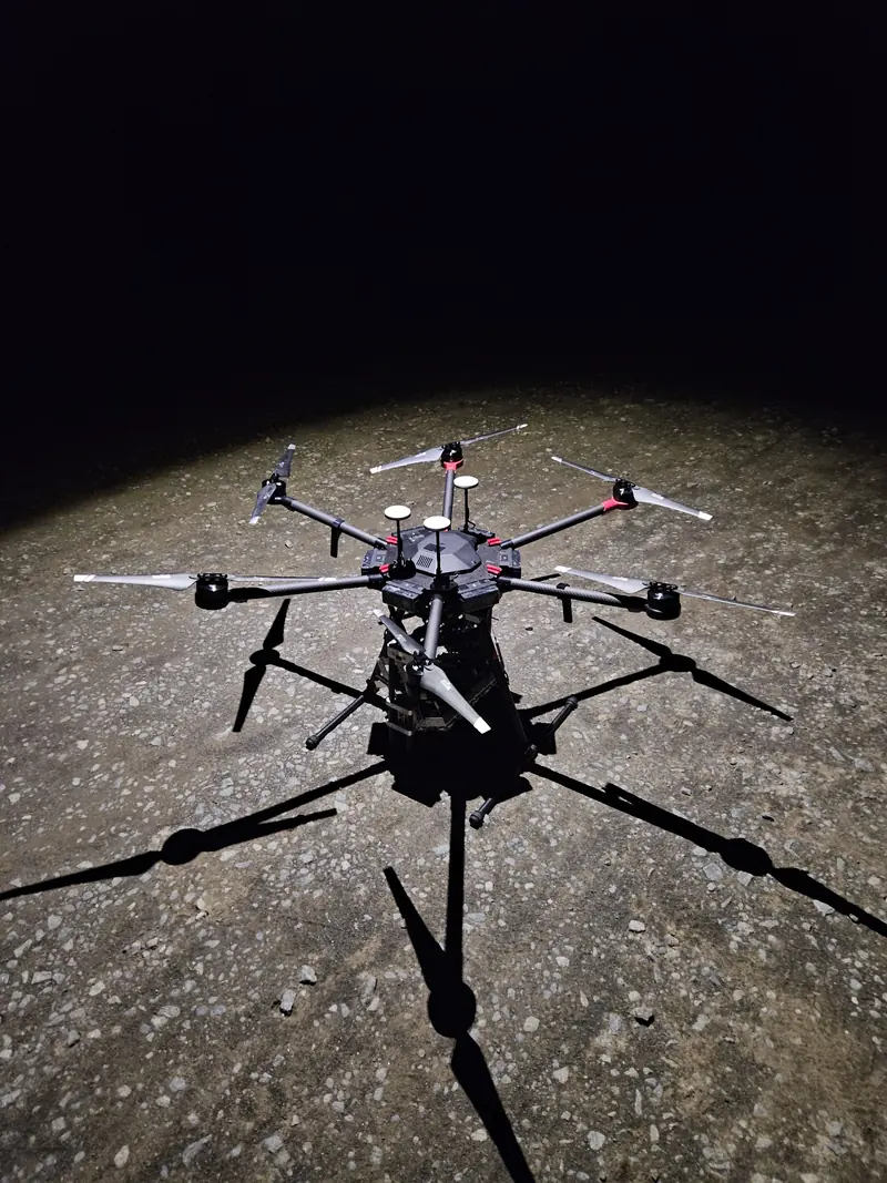 Lichtdrohne DJI M600 nachts startklar am Boden, von einem Scheinwerfer angestrahlt