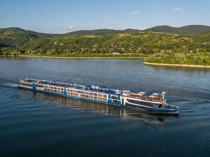 Flusskreuzfahrtschiff MS Ultra vor grüner Uferlandschaft, aus der Luft gefilmt