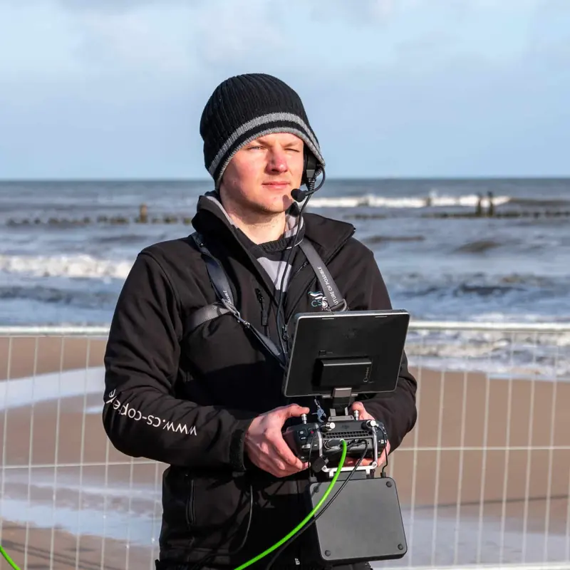 Christian Scheunert mit Fernsteuerung und Monitor bei einer Live-Übertragung am Strand